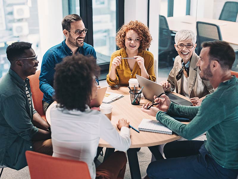 group of business people sitting around a table and talking